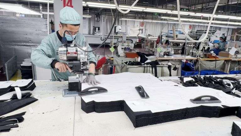Worker using Eastman straight knife cutting machine at clothing manufacturer china factory