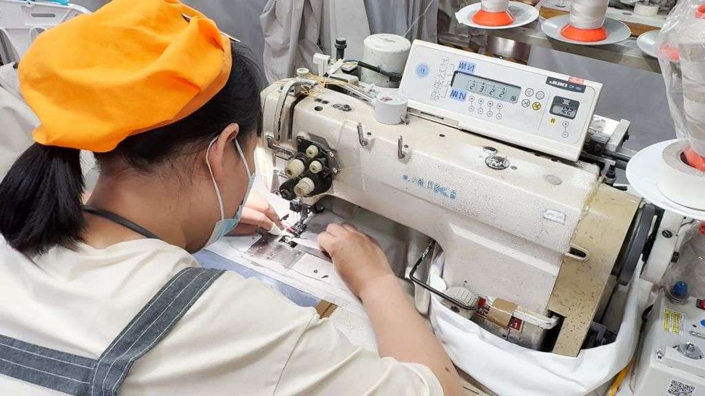 Worker operating JUKI industrial sewing machine for apparel manufacturing