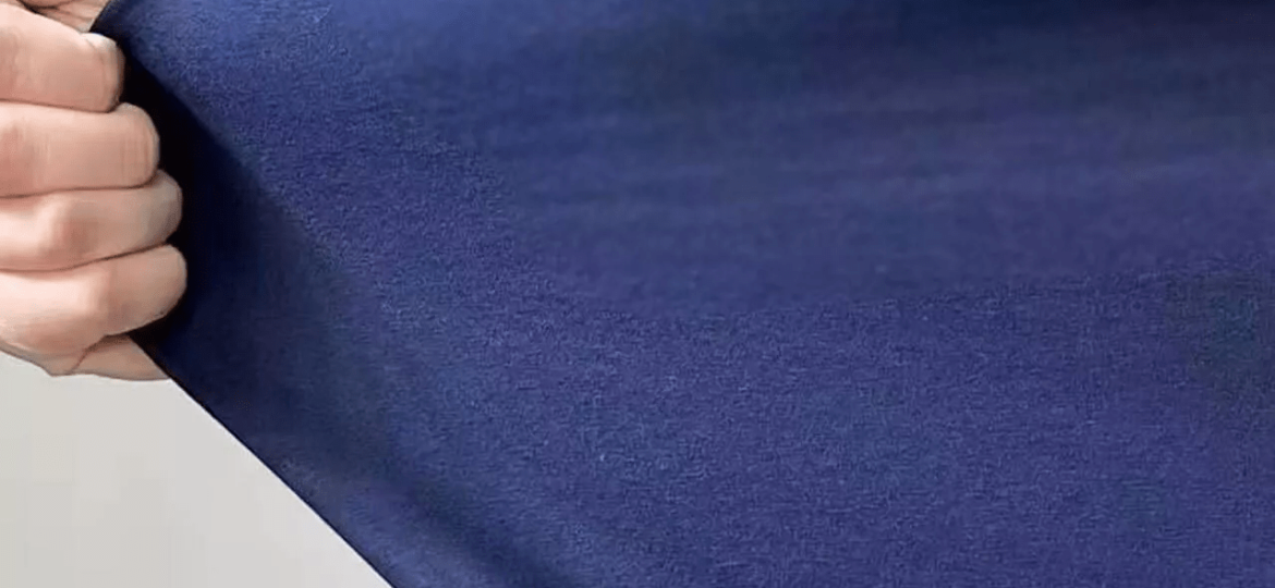 Close-up of heavyweight cotton jersey fabric showing dense knit texture and premium hand feel