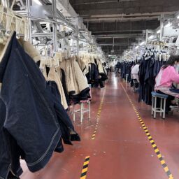 Garment factory production line showing sewing workers assembling denim and apparel in bulk manufacturing process