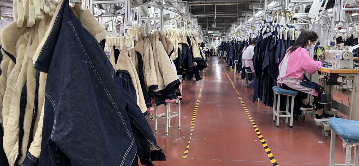 Garment factory production line showing sewing workers assembling denim and apparel in bulk manufacturing process