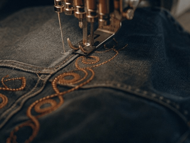 Fashion designers working on denim jacket tech packs and sketches during custom apparel development process