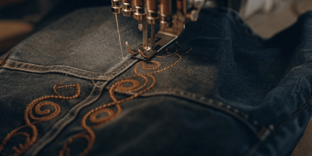 Fashion designers working on denim jacket tech packs and sketches during custom apparel development process