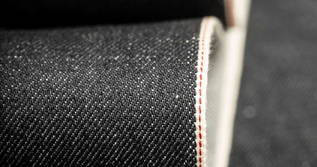 Close-up of raw selvedge denim fabric edge showing authentic selvedge weave line