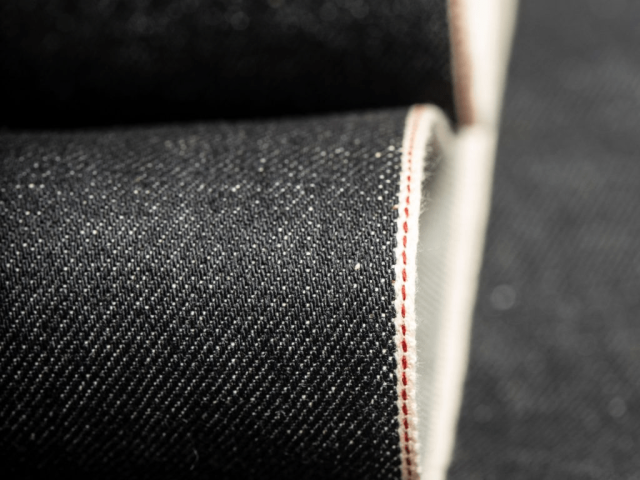Close-up of raw selvedge denim fabric edge showing authentic selvedge weave line